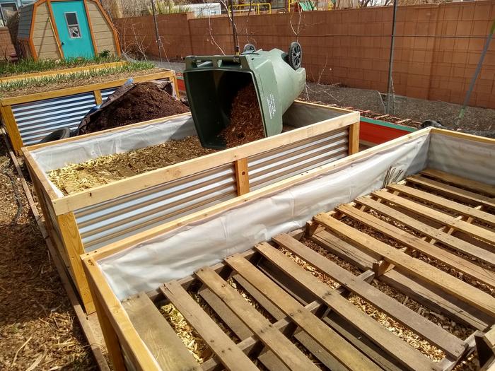 backfilling raised beds with wood chips on top of pallets.