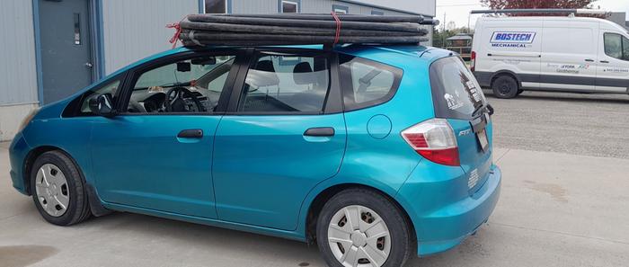 Ground source heat pump feeder pipes strapped to the roof of a car for transport