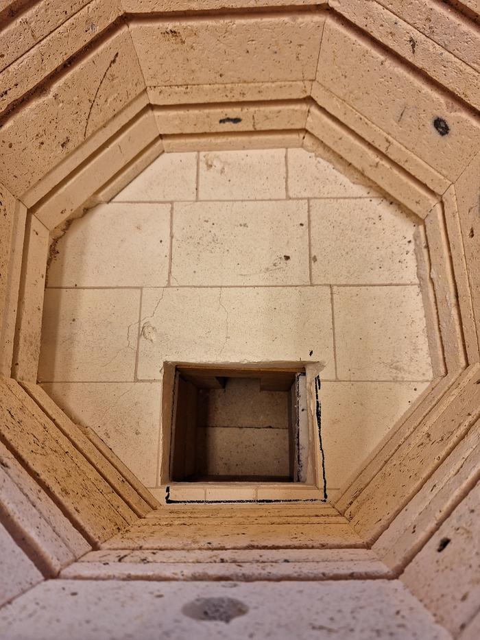 View into a pottery kiln with a hole cut in it for hot gasses from a riserless core