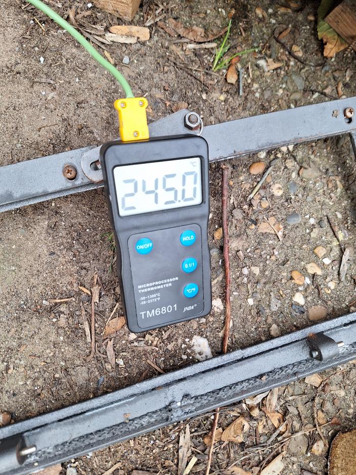 A temperature probe showing 245 degrees celsius in a rocket stove pottery kiln