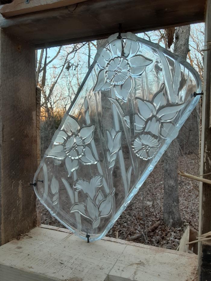 screws holding a piece of decorative window glass before the window is cobbed into place