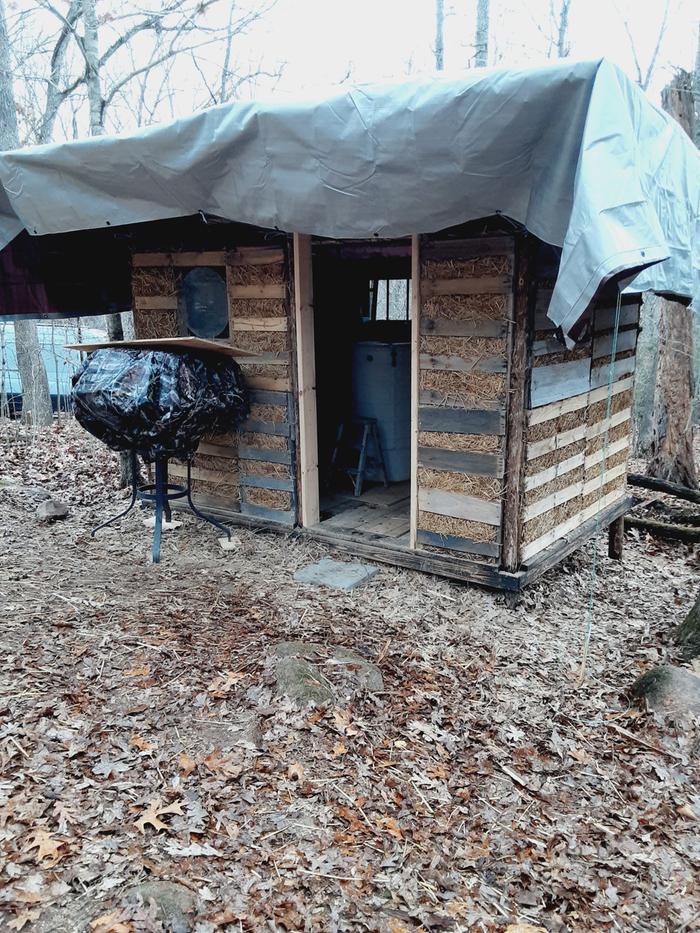 A light clay straw shed with a tarp over it