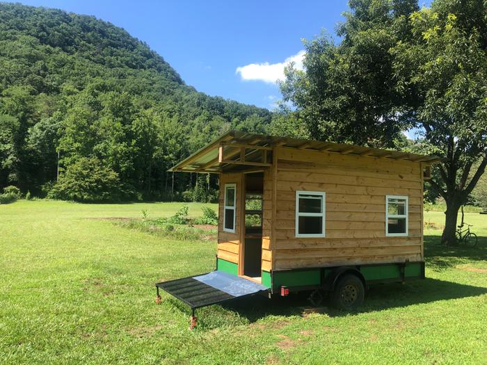 Exterior view of a tiny house on a green lawn against green hills in North Carolina