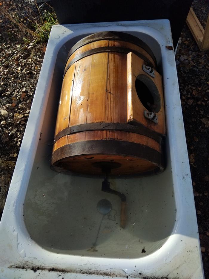 A wooden barrel manual washing machine soaks in water to expand the wood and seal cracks