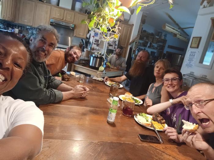 8 Adults in the kitchen of the Fisher Price House at Wheaton Laboratories. There is a wood table