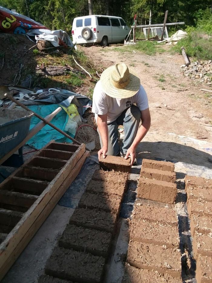 a gentleman flips adobe bricks on their side so that they can dry