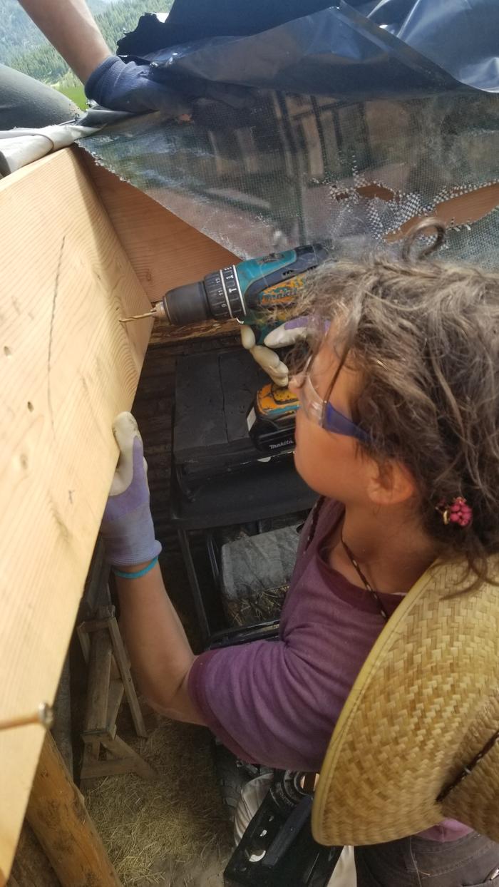 Jaqi Drilling a clearance hole to tie in a roof stick