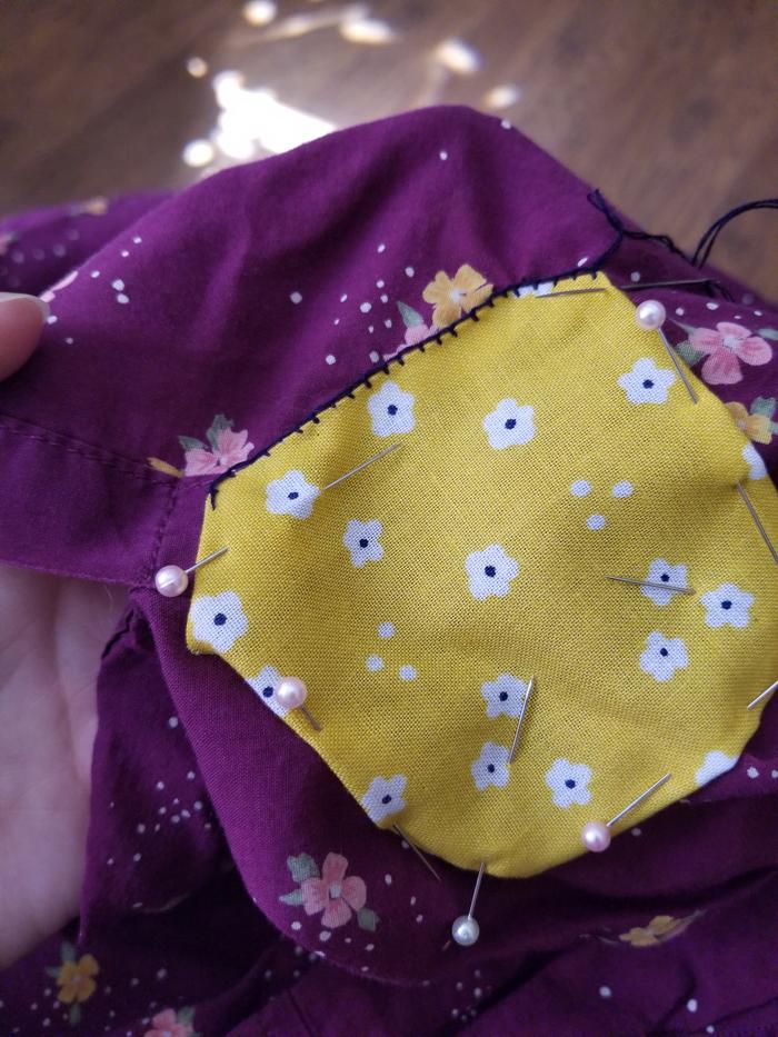 sewing a yellow patch onto a puple shirt