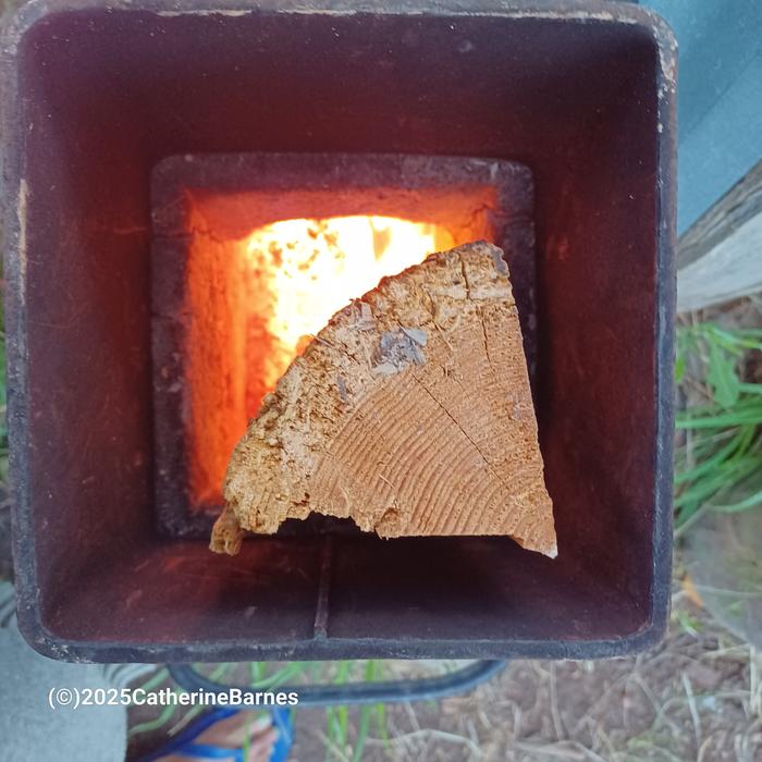 a split piece of firewood in the feed tube of a rocket water heater