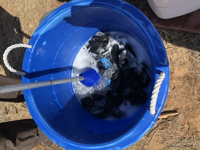 Clothes in bucket, washing with clothes plunger