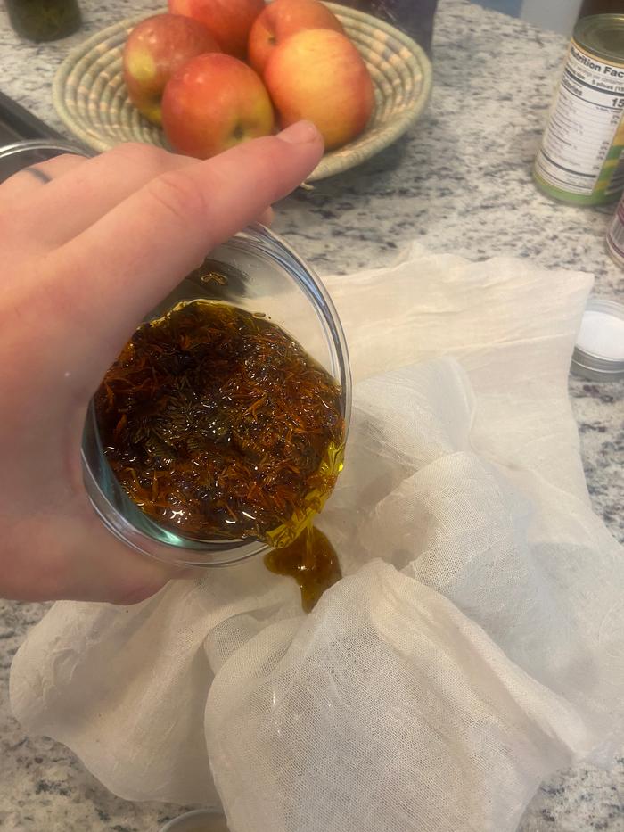 straining Calendula flowers from hot oil for making salve