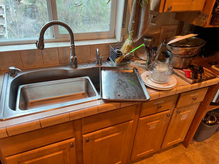 Dishes next to the sink with water catchment pan in 