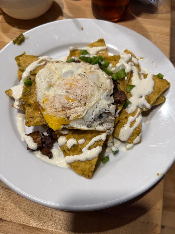 Chips in sauce, “steak”, jalapeños and onions, a fried egg, cilantro crema 