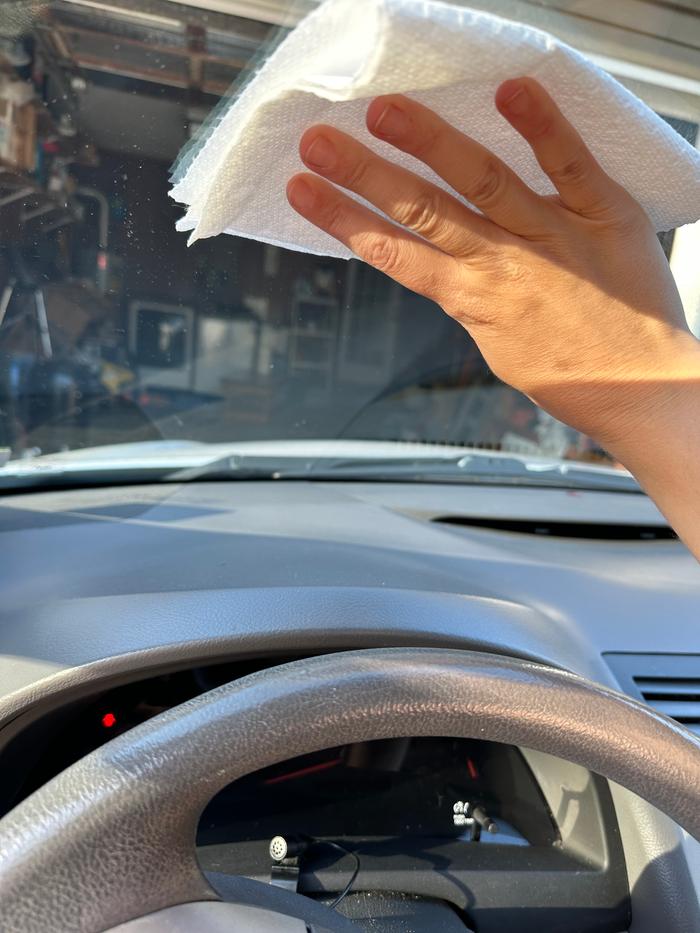 wiping inside of windshield with paper towel after spraying with water