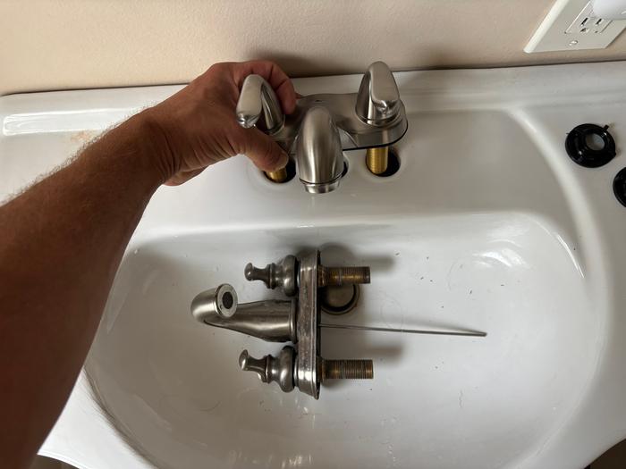 Old faucet removed and the new one being installed 