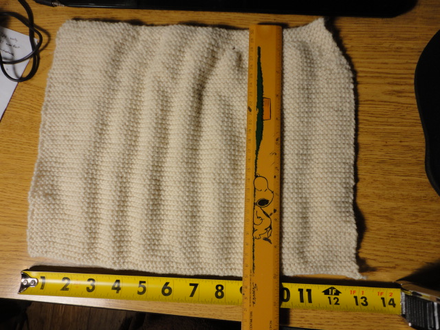 The final knit cotton dishcloth with measuring devices to show size.