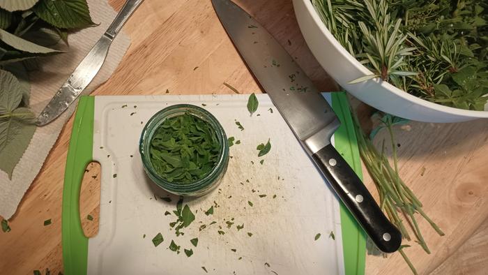 Add chopped oregano to jar and stir. Continue to fill jar with leaves until it is loosely full, stirring mixture with a knife or chipstick if needed.