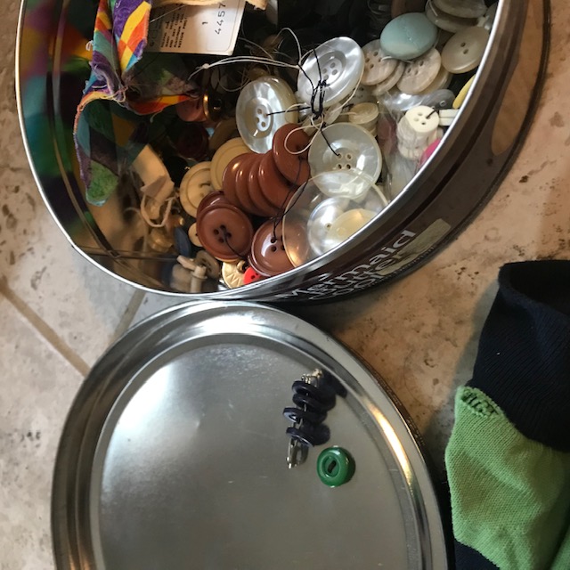 Buttons on the tin top secured by a safety pin to keep them matched