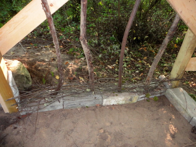 Some salvage half cinderblocks form the base the woven walls sit on. Here I am just starting to do the branch weaving.