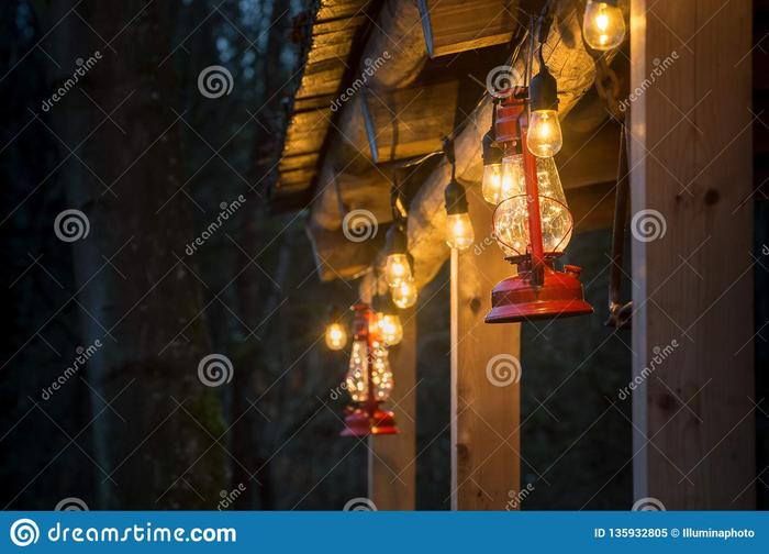 [Thumbnail for red-metal-storm-lantern-hung-outside-rustic-log-cabin-antique-style-glass-hurricane-alongside-string-editon-lightbulbs-135932805.jpg]