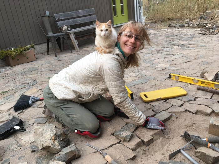 Lara balancing a cat and fitting a rock for the floor 