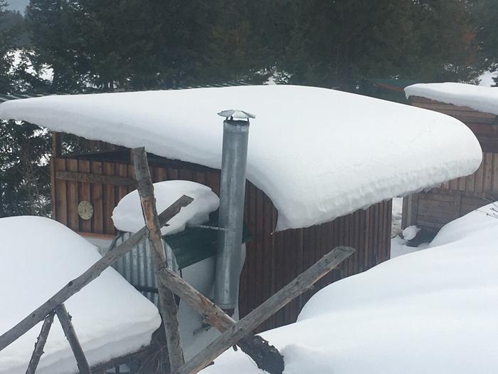 The snow curls off the metal roof as it slowly melts