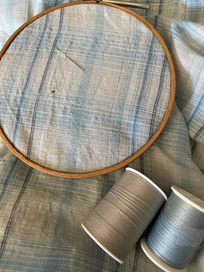 Hole set up in embroidery hoop to keep the fabric taut, with needle and the two colors of thread. The grey “reads” much closer to the ground color than any other thread I had. 