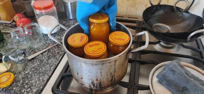 Pulling jam jars out of a boiling water bath with rubber gloves