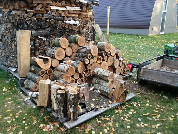 A big pile of wood with a garden tractor