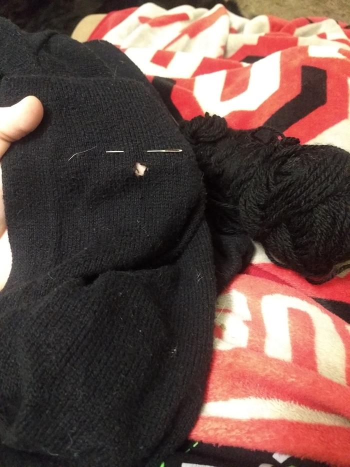 The hole in my cardigan, plus the yarn and needle I used to fix it.