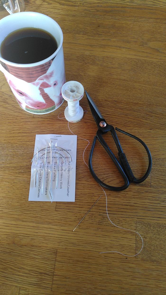 Tools of the art. Simple machine thread (laid double), "leather glove"-needle, scissors, coffee in pig mug.