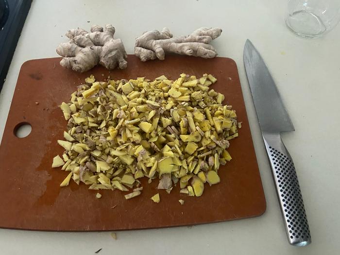 Ginger root all chopped up on a cutting board with a knife beside it