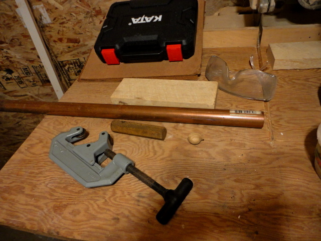 Some of the starting materials, a copper pipe, the tube cutter, a piece of scrap hex steel, and a wood block.