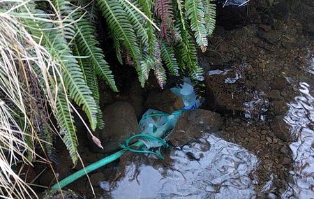 Plastic bottle held down with stones under water