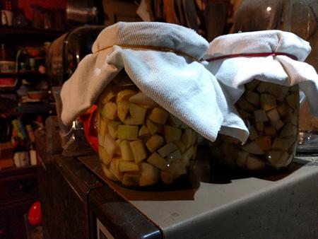 glass jars full of chopped vegetables covered with white cotton