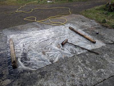 washing off plastic sheet with hose and broom