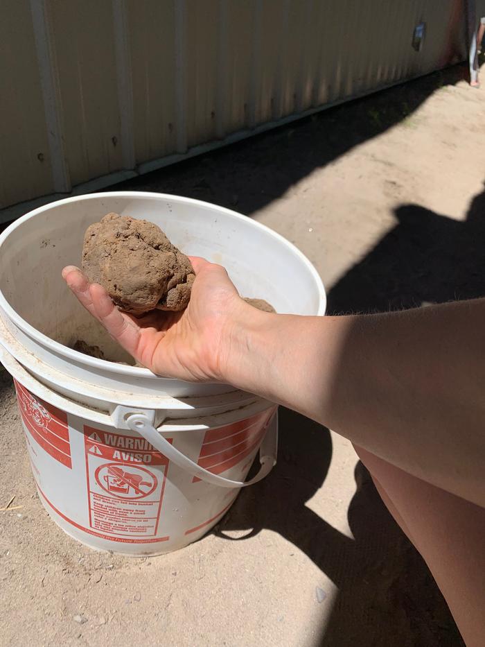 hand-holding-raw-clay-from-test-trench