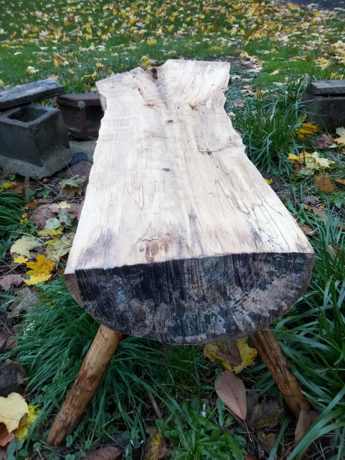 A completed staked log bench out in the grass