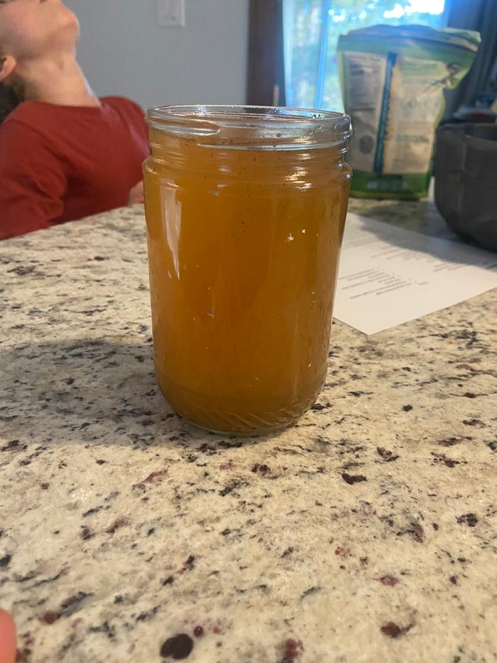 a throat gargle in a glass jar on a stone countertop, a boy is gargling in the background
