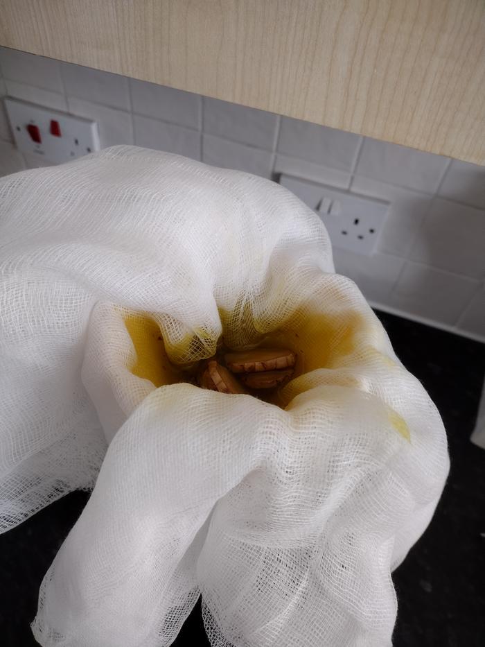 Straining the oil with a cheesecloth