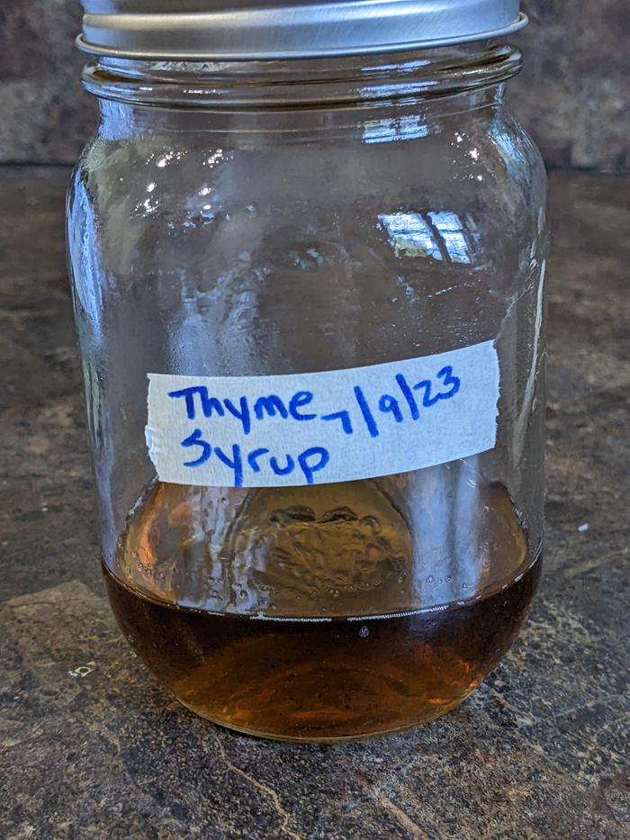 The finished strained thyme syrup in its labeled jar