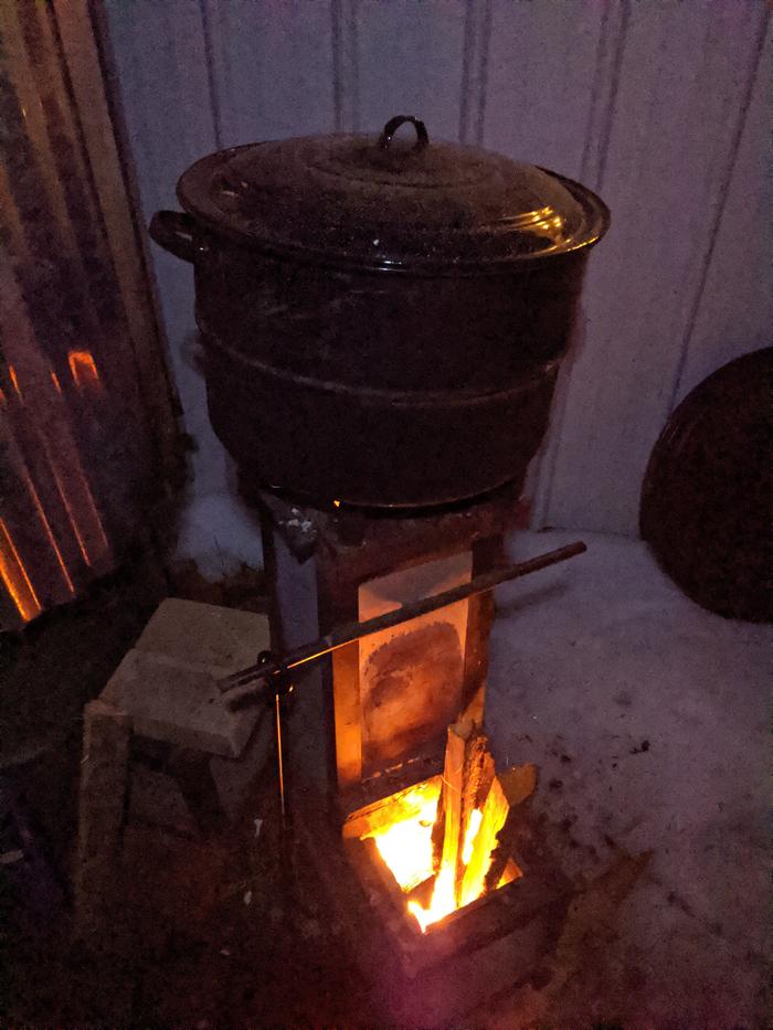 Using the j-tube to heat several gallons of water for each meal. High efficiency low tech - it's still a kick to switch rocket on from the wood feed to the riser with a little air. 