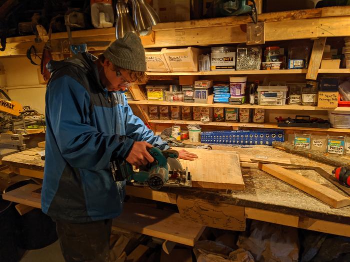 Reid using the circular saw to cut the square out after using the framing square to mark it up. 