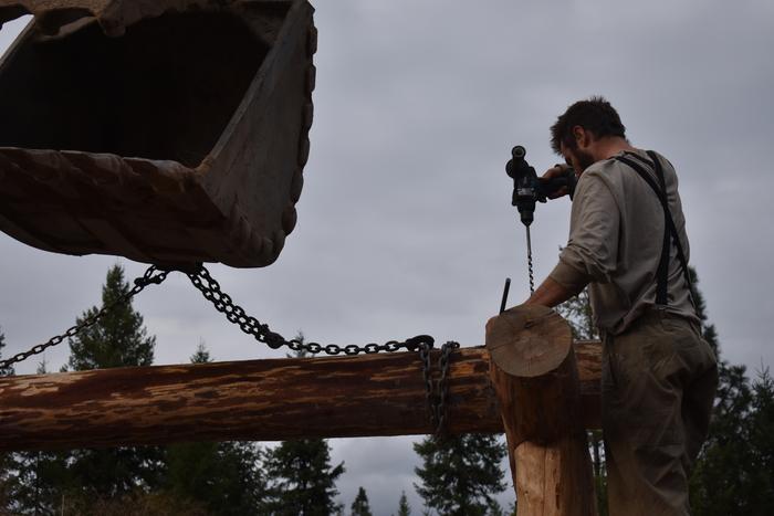 Josiah drilling hole for metal pin after lowering beam into place.