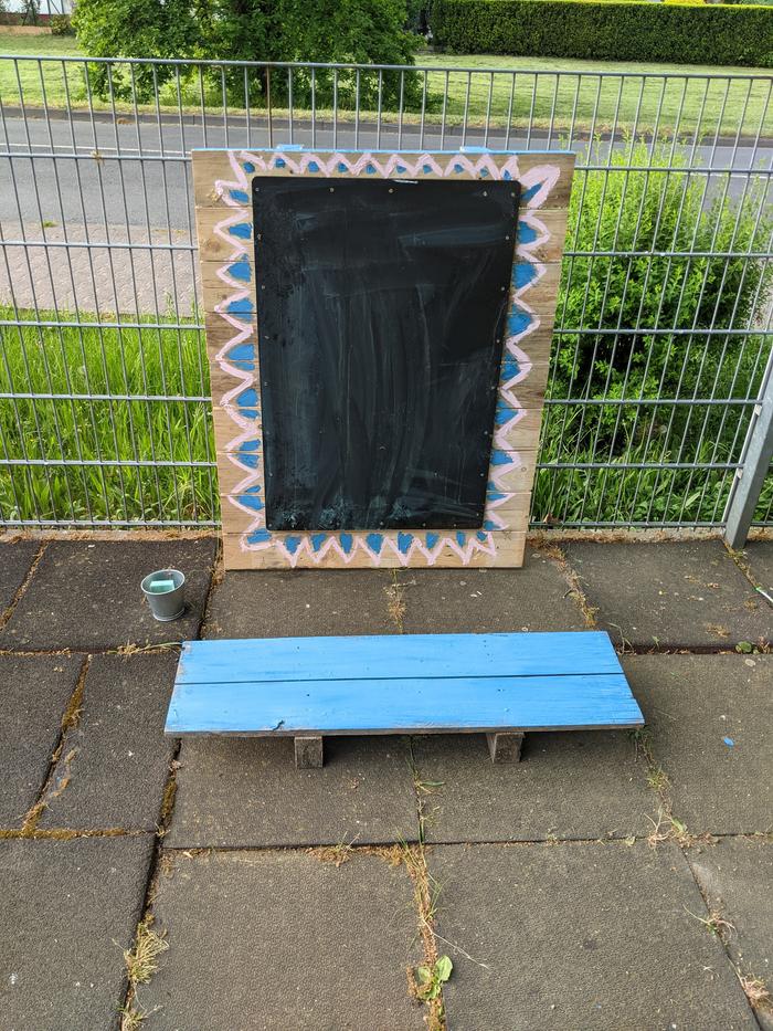 I moved the second blackboard down to a more kid-friendly height; I mounted it to a pallet and screw-hooked the top of the pallet to the fence.