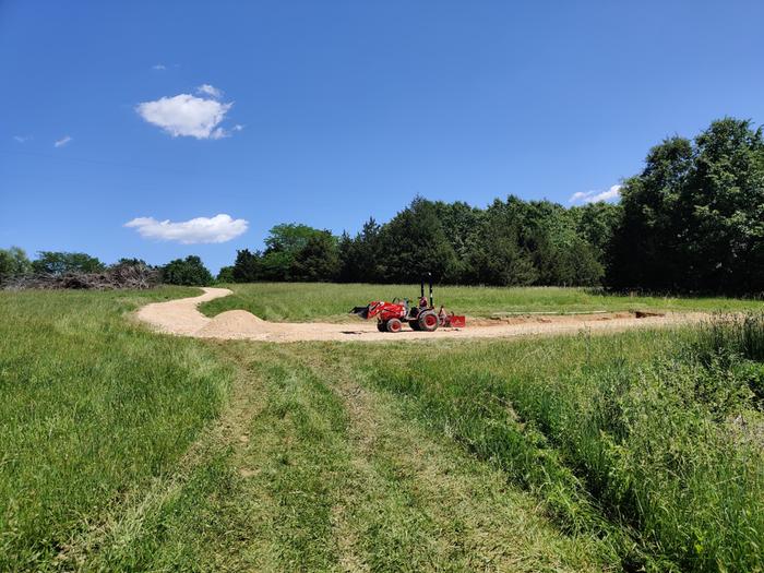 driveway with a pile of gravel and a tractor to move it