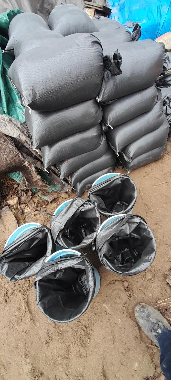 Very full sandbags with some waiting to be filled in maple sugar buckets