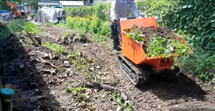 tracked powered wheelbarrow full of dirt with some plants