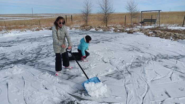 shoveling snow on a frozen pond