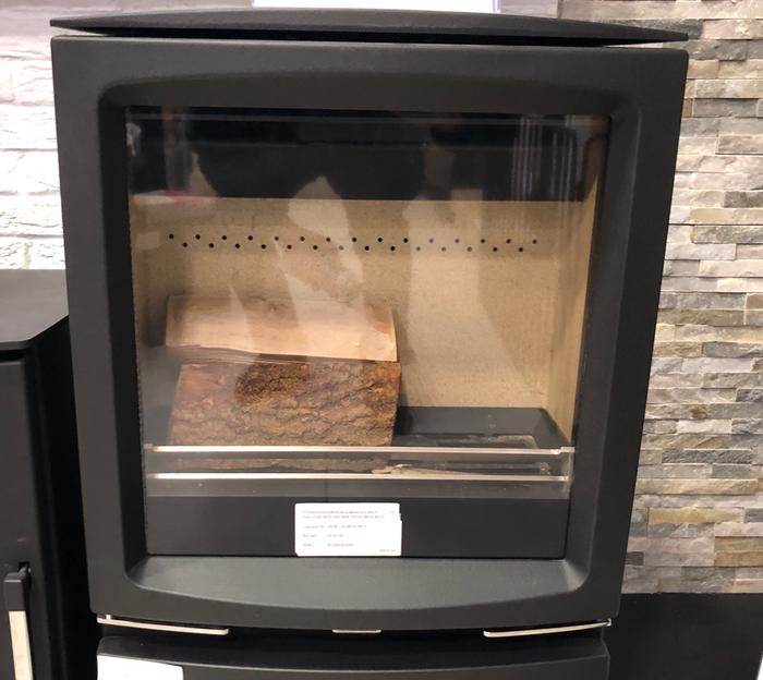 A vermiculite lined wood stove with holes for secondary air at the back of the combustion chamber